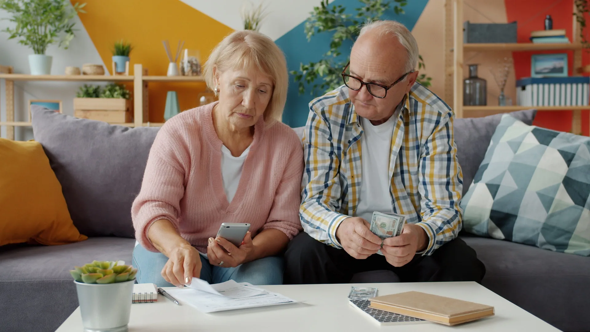 Couple senior comptant des pièces et des billets devant des documents